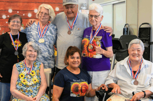 elderly residents pose wearing medals, around Dinora Negrete, the staff member who started the "walk to Kansas" challenge.